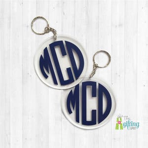May include: Two clear acrylic keychains with a silver key ring. Each keychain features a navy blue monogram with the letters "MCD".