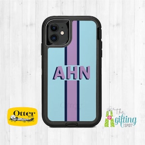 May include: A black OtterBox phone case with a light blue and purple striped design. The case has a clear back and a black frame. The letters "AHN" are printed in purple on the back of the case.