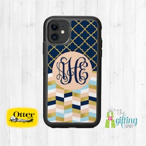 May include: A black OtterBox phone case with a navy blue and gold geometric pattern. The case has a monogrammed circle with the initials "HE" in a script font. The case is designed for an iPhone.