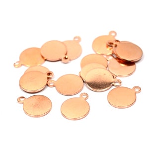 May include: A group of 12 round, copper-coloured metal charms with a loop at the top. The charms are smooth and have a slightly shiny finish.