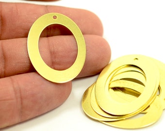 May include: A close-up of a stack of gold oval-shaped metal rings with a hole in the center. The rings are about 1 inch in diameter.
