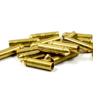 May include: A pile of gold-colored metal electrical connectors with a pointed tip on one end and a hollow cylinder on the other end.