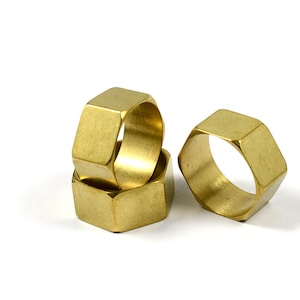 May include: Three gold hexagonal rings stacked on top of each other. The rings are smooth and shiny.