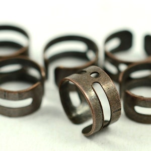 May include: Six copper-toned metal rings with a cutout design. The rings are stacked and arranged in a circular pattern.