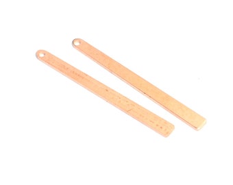 Puede incluir: Dos colgantes de barra de metal de color oro rosa con un agujero en la parte superior. Las barras miden aproximadamente 3,8 cm de largo y 0,6 cm de ancho.