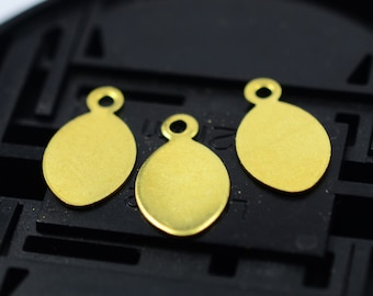 May include: Three small, gold-colored oval charms with a loop at the top for jewelry making. The charms are smooth and shiny, with a simple, elegant design. They are arranged on a black surface.