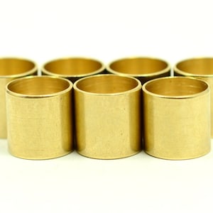 May include: Seven gold-colored metal rings or spacers, arranged in a semi-circle on a white background.