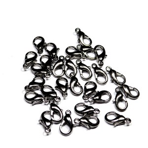 May include: A pile of silver-toned lobster clasps, a type of fastener used for jewelry making.