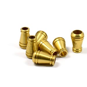 May include: A group of six gold-colored metal caps or tips. The caps are cone-shaped with a rounded top and a slightly flared base.