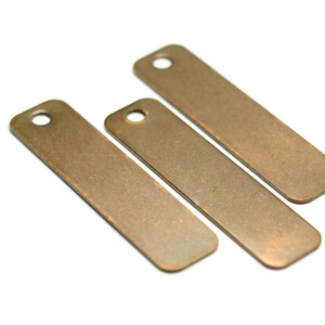 May include: Three rectangular metal tags with a hole at the top. The tags are a rustic copper color.
