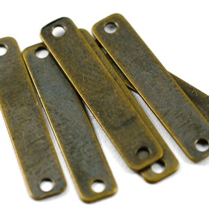 May include: Six antique brass rectangular metal tags with holes at each end. The tags have a distressed, aged finish.