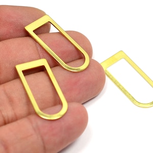 Op de afbeelding: Drie gouden metalen ringen met een rechthoekige vorm en een afgeronde bovenkant. De ringen zijn ongeveer 2,5 cm lang.