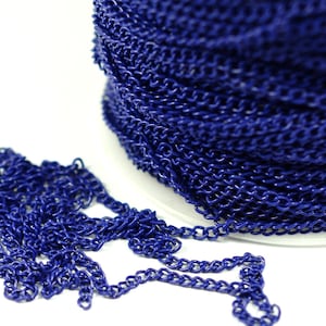 May include: A spool of dark blue chain, with a section of the chain lying loose in front of the spool. The chain is made of metal and has a smooth, polished finish.