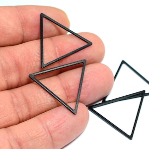 Pode incluir: Quatro formas triangulares de metal preto, cada uma com um tamanho e uma orientação ligeiramente diferentes.