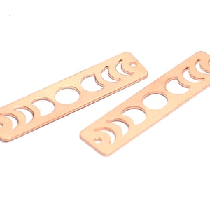 May include: Two rose gold metal bar charms with a moon phase design. Each charm has eight different moon phases cut out.