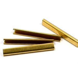 Puede incluir: Cuatro tiras de metal de color dorado con un borde dentado. Las tiras se utilizan para asegurar tela u otros materiales.