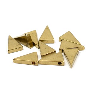 May include: A group of ten gold-coloured triangle-shaped metal beads with a hole in the centre of each bead.
