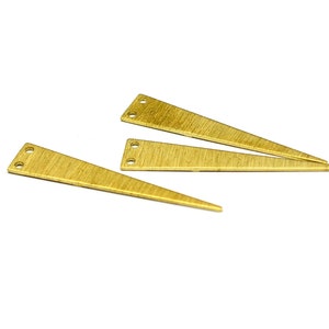 May include: Three gold-colored metal triangle shapes with two holes each. The shapes are arranged in a triangular pattern.