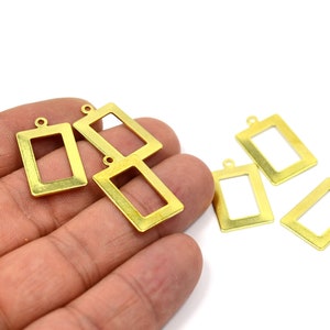 May include: Six gold-toned metal rectangular picture frame charms with a loop at the top for hanging.
