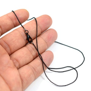 Op de afbeelding: Een zwarte ketting met een karabijn sluiting. De ketting is gemaakt van kleine, ronde kralen.