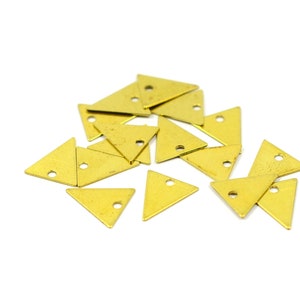 Può includere: Un gruppo di 15 ciondoli triangolari in metallo color oro con un foro al centro di ogni triangolo.