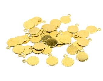Puede incluir: Un montón de abalorios redondos de metal dorado con un bucle en cada abalorio. Los abalorios están esparcidos sobre un fondo blanco.