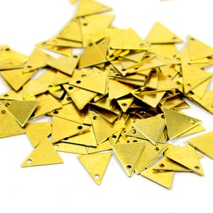 May include: A pile of gold-colored metal triangle charms with two holes in each charm.