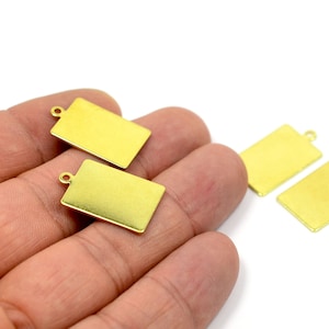 May include: Four gold-colored metal rectangular tags with a small loop at the top. The tags are blank and ready for personalization.