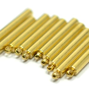 May include: A set of ten gold-colored metal tubes with a loop at one end. The tubes are arranged in a semi-circle, with the loops facing the viewer.