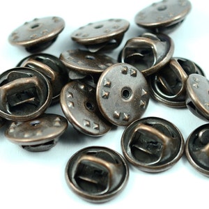 Puede incluir: Un mont&oacute;n de 15 botones de cierre de metal de color bronce antiguo con un dise&ntilde;o decorativo. Los botones tienen una parte superior redonda con un peque&ntilde;o agujero en el centro y un bucle en la parte posterior.