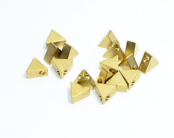 May include: A group of 15 gold-colored triangle-shaped metal beads with a hole in the center of each bead.