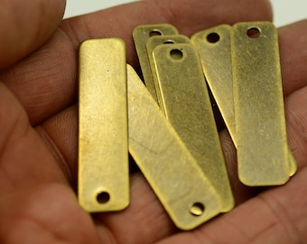 May include: A set of seven antique brass rectangular tags with a hole at the top. The tags are slightly worn and have a rustic look.