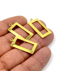 May include: Three gold-colored metal rectangular frames with a small loop at the top. The frames are open and have a smooth, polished finish.