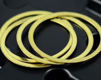May include: Four gold-colored metal rings stacked on top of each other. The rings are smooth and have a shiny finish.