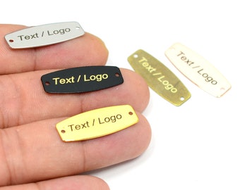 May include: Four metal tags with rounded edges and two holes. The tags are silver, black, gold, and brass. Each tag has the text "Text / Logo" engraved on it.