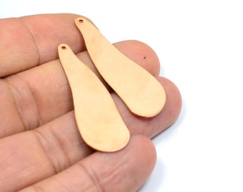 Puede incluir: Dos piezas en blanco para pendientes de metal sin terminar, de color marrón claro, en forma de lágrima, con un agujero en la parte superior.