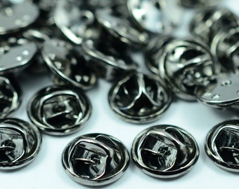 May include: A pile of black metal pin back buttons. The buttons are round and have a smooth, shiny finish.