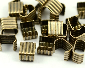 Puede incluir: Un grupo de cierres de metal dorado antiguo con un diseño acanalado. Los cierres son pequeños y tienen forma cuadrada.
