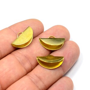 May include: Three gold-colored metal half-circle clasps with a loop at the top. The clasps are on a hand.