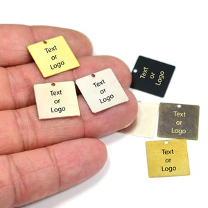 May include: Six square metal tags with a hole at the top. Each tag is a different color: gold, silver, black, brass, and two shades of gold. The text "Text or Logo" is engraved on each tag.