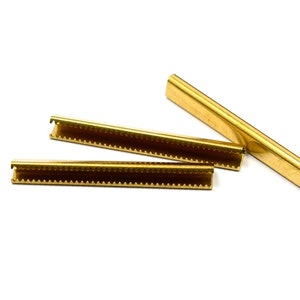 Puede incluir: Tres tiras de metal dorado con un borde dentado. Las tiras se utilizan para sujetar tela a un marco.