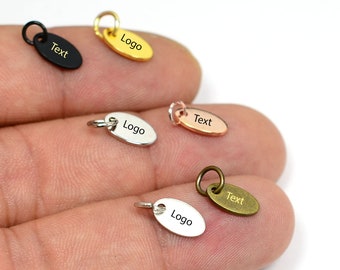 May include: Oval-shaped metal charms in various colors, including black, gold, silver, and bronze. Each charm has a small loop for attachment and features the word "Text" or "Logo".