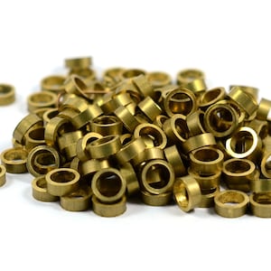 May include: A pile of small, gold-coloured metal rings. The rings are all the same size and shape, and they are arranged in a random pattern.