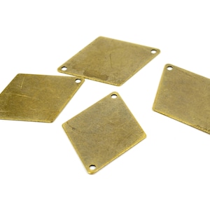 May include: Four antique gold diamond-shaped metal charms with two holes each.
