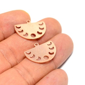 May include: Two gold-toned metal charms shaped like half moons with cut-out crescent moon designs. The charms have a hole at the top for attaching to jewelry or other crafts.