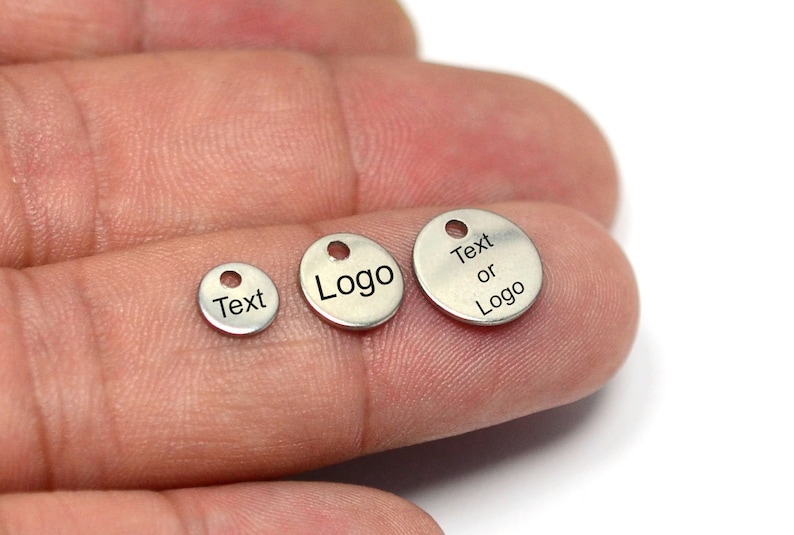 May include: Three silver metal round tags with holes for hanging. The smallest tag says "Text", the middle tag says "Logo", and the largest tag says "Text or Logo".