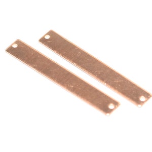 May include: Two rose gold metal bar shapes with holes at each end. The bars are flat and rectangular.