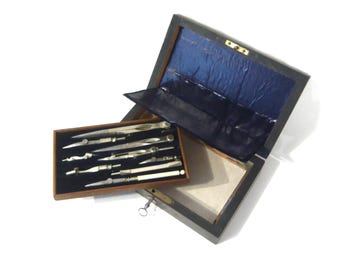 Set di compassi con chiave e 12 utensili e accessori in acciaio e ottone, fine XIX/inizio XX secolo. Custodia per compasso, accessori da disegno.