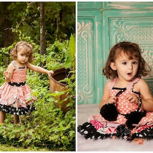 以下が含まれることがあります： ピンクと黒のドット柄のドレスを着た若い女の子。彼女は緑の植物と木のある庭に立っています。