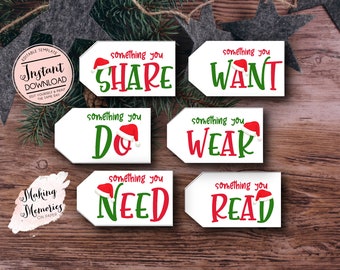Può includere: Bigliettini bianchi con testo rosso e verde, ognuno sormontato da un cappello di Babbo Natale. I bigliettini recitano "SHARE", "WANT", "DO", "WEAR", "NEED" e "READ". I bigliettini sono su una superficie di legno con decorazioni natalizie.